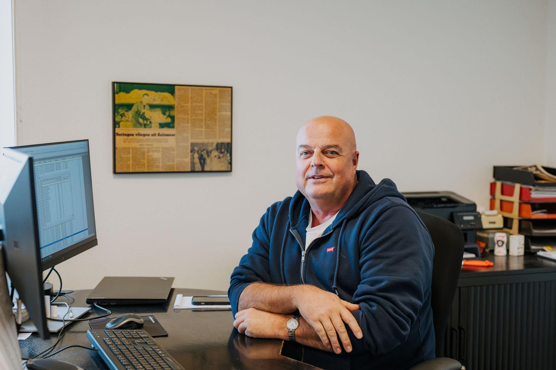 Medewerker van Tuning zit aan zijn bureau op kantoor, werkzaam met administratieve en logistieke gegevens in een rustige werkomgeving.