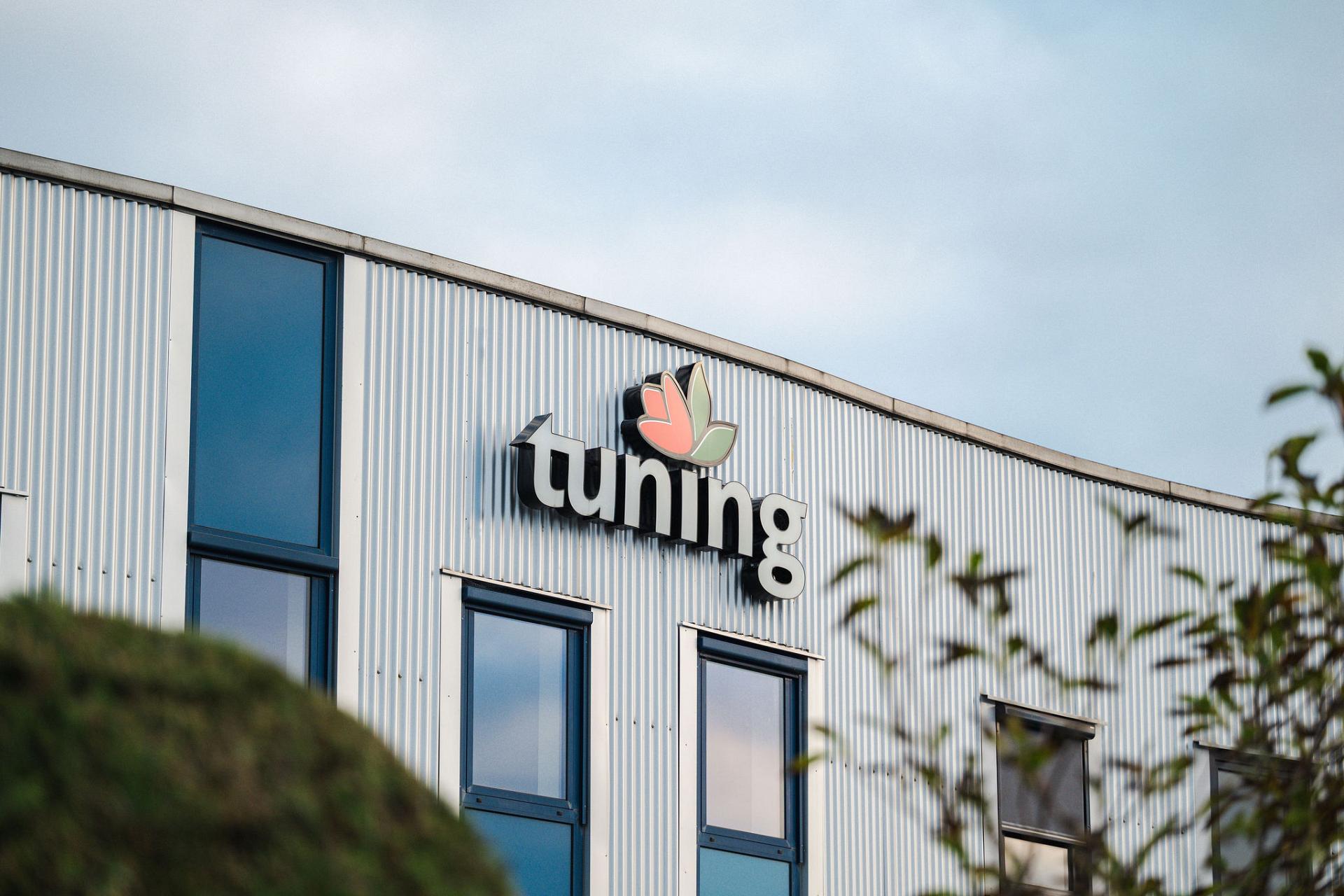 Außenansicht des Firmengebäudes von Tuning in Aalsmeer, mit dem markanten Logo an der Fassade des Hauptsitzes.